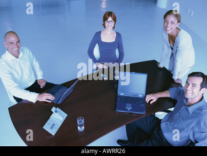 Geschäftsleute um Schreibtisch, lächelnd, erhöht, Ansicht Stockfoto