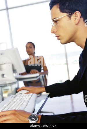 Geschäftsmann und Geschäftsfrau arbeiten an Schreibtischen, Seitenansicht des Menschen im Vordergrund Stockfoto