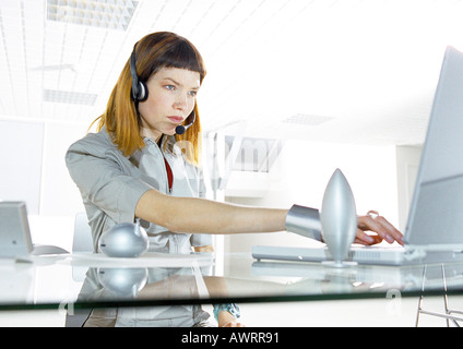 Frau am Schreibtisch tragen Kopfhörer im Büro Stockfoto