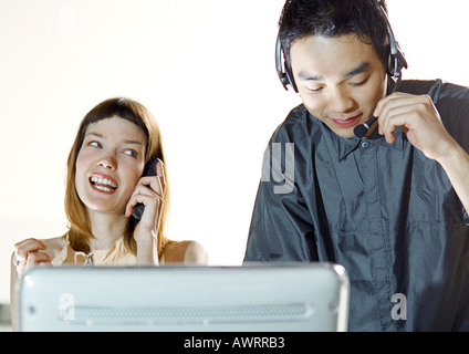 Mann trägt Kopfhörer, Frau mit Handy Stockfoto