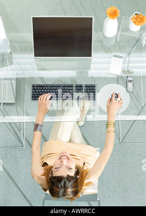 Frau am Tisch mit Bildschirm und Tastatur, hoher Winkel vew Stockfoto