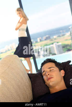 Mann schläft auf Sofa, Frau im Hintergrund Stockfoto