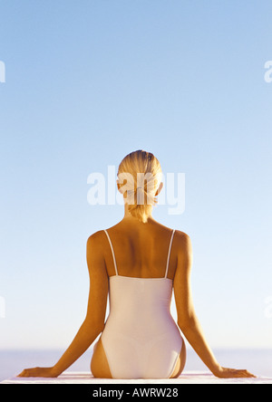 Frau in einteiliger Badeanzug, verteilt auf die Seite, Hüfte aufwärts, Rückansicht, blauen Himmel im Hintergrund Stockfoto