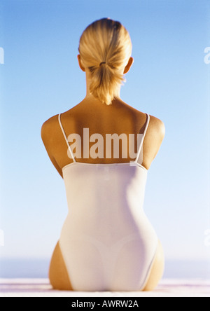 Frau im Badeanzug sitzt im Freien, Rückansicht Stockfoto