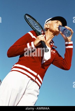 Reife Frau holding Tennisschläger und trinken aus der Flasche Wasser, niedrigen Winkel Ansicht Stockfoto