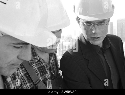 Drei Männer tragen Schutzhelme, Nahaufnahme, b&w Stockfoto