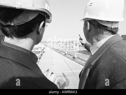 Zwei Männer tragen schwer Harts sprechen, Rückansicht, b&w Stockfoto