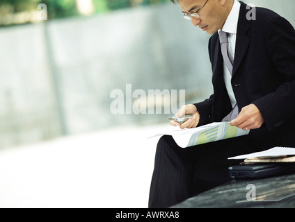 Geschäftsmann, draußen sitzen, Prüfung von Dokumenten Stockfoto