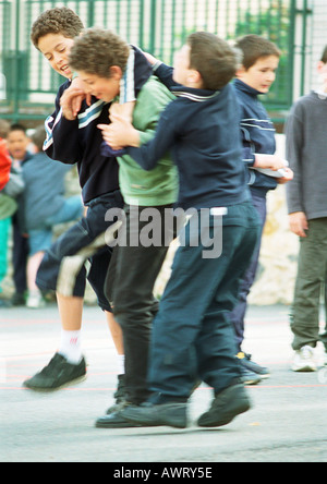 Kinder Playfighting im Schulhof Stockfoto