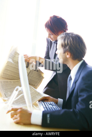 Unternehmer und Unternehmerin, die Zeitung zu betrachten Stockfoto