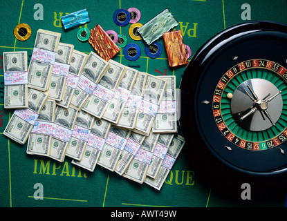 ROULETTE-RAD-CHIPS UND BÜNDEL VON 100 US-DOLLAR-NOTEN Stockfoto