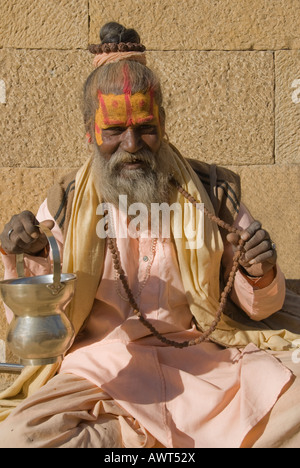 Porträt von einem älteren Sadhu mit Perlen und bronzene Schüssel gekleidet in Pastell Gewand in Jaisalmer, Rajasthan, Indien Stockfoto