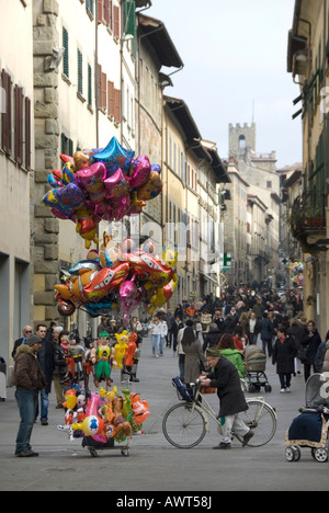 Ballon-Verkäufer und alten Mann Räder ein Fahrrad über den Abend Passeggiata in Corso Italia die Haupteinkaufsstraße von Arezzo Stockfoto