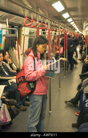 dh Mass Transit Railway MTR HONG KONG Mädchen Passagier Lesung Zeitung in U-Bahn Zug öffentlichen Verkehrsmitteln Reise U-Bahn U-Bahn Zeitung frau aus china Stockfoto