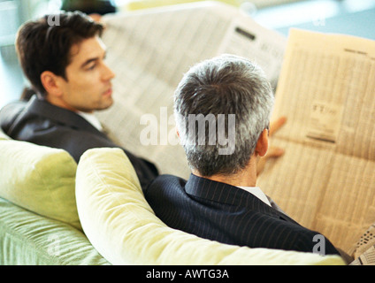 Geschäftsleute sitzen lesen Zeitungen, Sicht nach hinten, Kopf und Schultern Stockfoto
