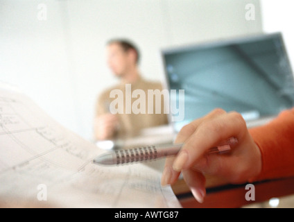 Zarte Frauenhand Stift über Tagesordnung, Mann verschwommen im Hintergrund zu halten Stockfoto
