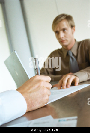 Geschäftsmann sitzt gegenüber zweite Geschäftsmann, Nahaufnahme von Hand schreiben Stockfoto