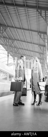 Geschäftsmann und Frau, von Angesicht zu Angesicht auf Bahnsteig, Ganzkörperansicht, b&w, vertikale Stockfoto