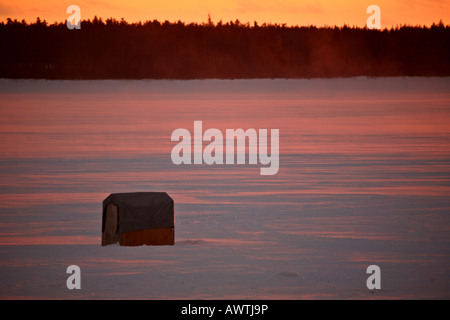 Eis Angeln Shack auf zugefrorenen See bei Sonnenuntergang Stockfoto