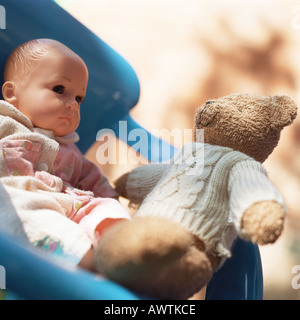 Teddybär sitzend auf Stuhl mit Babypuppe Stockfoto