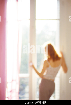 Frau aus Fenster, Sicht nach hinten, drei Quartal Länge, verwischt. Stockfoto