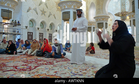 Männliche und weibliche Reiseleiter in traditioneller Kleidung in der Sheikh Zayed Moschee, Abu Dhabi, VAE. Stockfoto