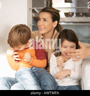 Kinder sitzen auf Mutters Schoß, Mutter macht Gesicht Stockfoto