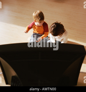 Kinder sitzen auf dem Boden zusammen, Fernsehen im Vordergrund Stockfoto