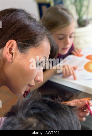Mutter mit Kind, Tochter im Hintergrund lesen. Stockfoto