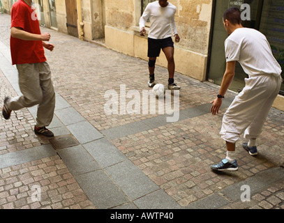 Männer treten Fußball in der Straße Stockfoto