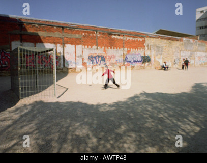 Fußball auf Schmutz Hof neben Graffitiwand spielt Stockfoto