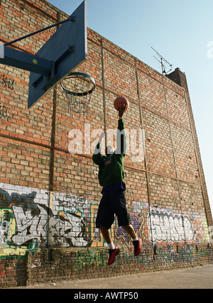 Mann geht für einen Basketball-Lay-up neben Graffitied Wand Stockfoto