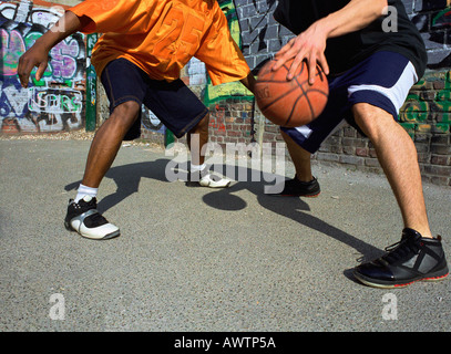 Mann dribbling Basketball, Gegner zu blockieren, neben Graffitied Wand, Nahaufnahme Stockfoto