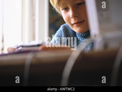 Kleiner Junge betrachtet man Videospiel, Nahaufnahme, Computer und Schreibtisch im Vordergrund unscharf Stockfoto