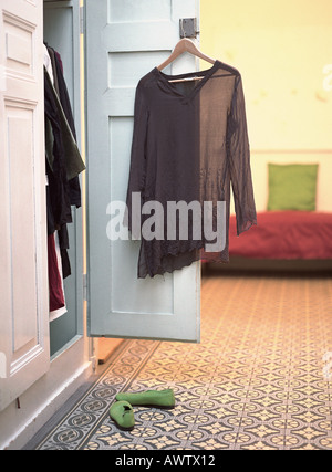 Offener Schrank mit Bluse von Tür und Paar Schuhe am Boden hängen Stockfoto