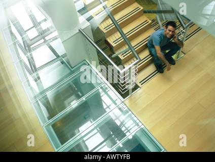 Man sitzt auf der Treppe reden über Handy nachschlagen, Ansicht von oben Stockfoto