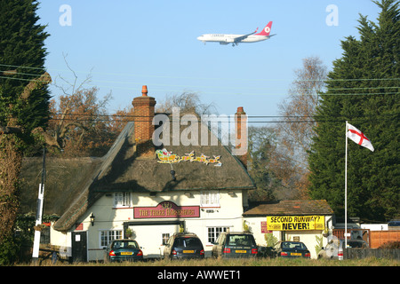 Ein Flugzeug fliegt über das Three Horseshoes Public House auf seinem Ansatz für die Landung in Stansted Flughafen, Essex, England, UK. Stockfoto