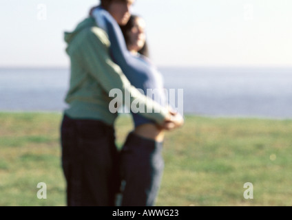 Junges Paar, umarmen, stehend im Rasen in der Nähe von Wasser Stockfoto