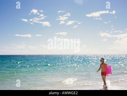 Mann zu Fuß ins Meer mit Luftmatratze Stockfoto