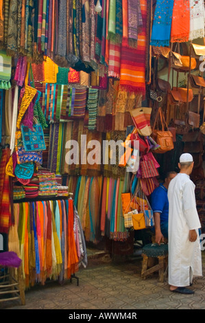 Vertikale hautnah von einem Mann in einem weißen Kaftan draußen ein buntes Textilgeschäft auf Rue Souk Smarine in Marrakesch. Stockfoto