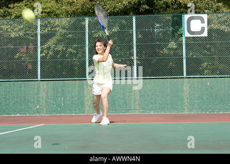 Junge Frau, die Tennis spielen auf Freiplatz Stockfoto