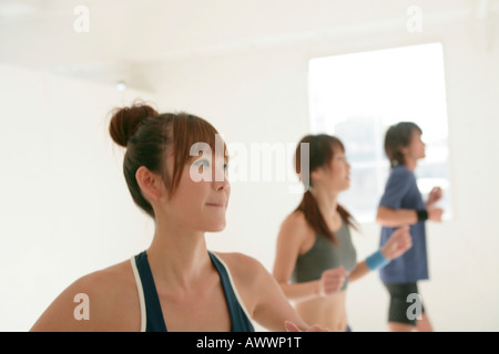 Zwei junge Frauen und Mann drinnen trainieren Stockfoto