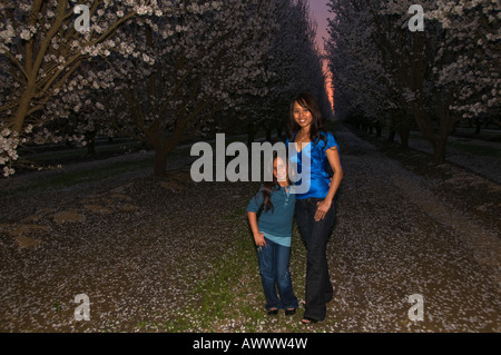 Mutter Tochter Hände in Taschen Sonnenuntergang Mandel Obstgarten Stockfoto