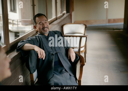 Älterer Mann sitzt im Stuhl auf Flur Stockfoto