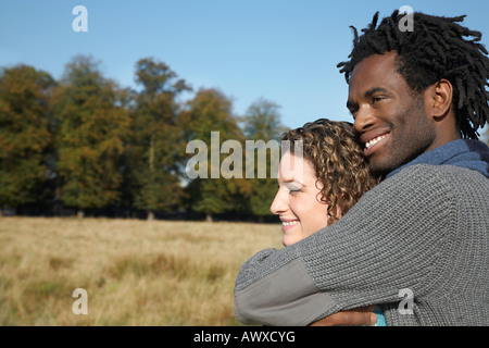 Paar in Feld umarmen Stockfoto