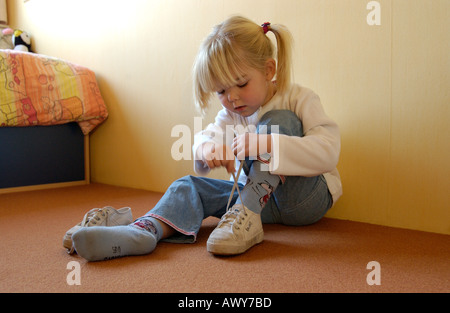 Kleine Mädchen ihre Schuhe anziehen Stockfoto