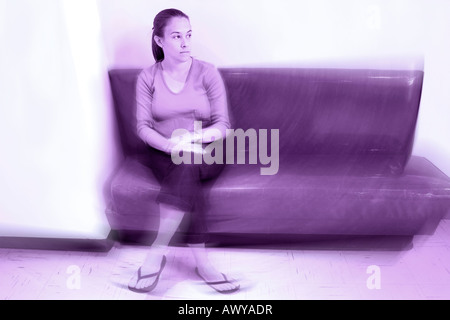 Eine junge Frau sitzt alleine auf einer Bank suchen, ängstlich oder depressiv Stockfoto