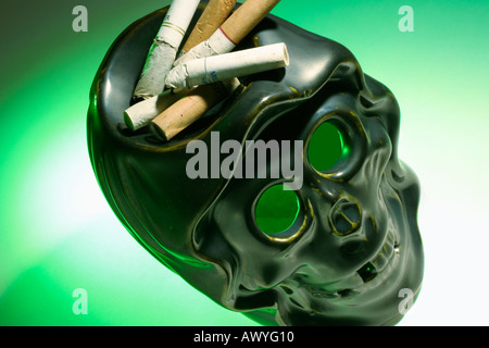 Zigarettenkippen auf Schädel Aschenbecher Stockfoto