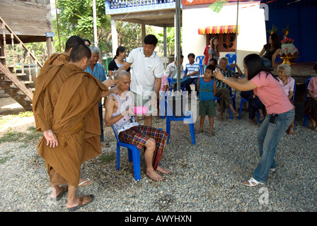 Frau nimmt ein Foto als zwei thailändischen buddhistischen Mönchen und Familienmitglieder untersuchen die neu rasierten Kopf ein Novize Stockfoto