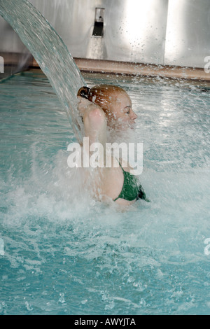 Junge Frau, die unter Wasserspray im Whirlpool Stockfoto